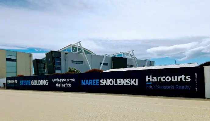 This hoarding signage for Harcourts at a racetrack creates a memorable branding opportunity in the community space.