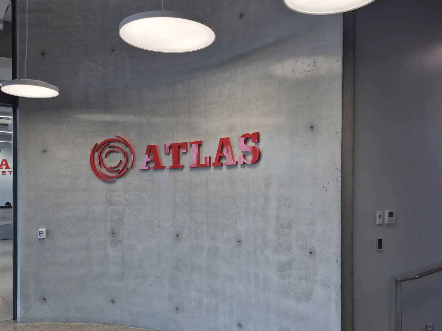 Large scale custom logo sign mounted on curved interior wall in reception area at Atlas Concrete. Sign by Displayworks.